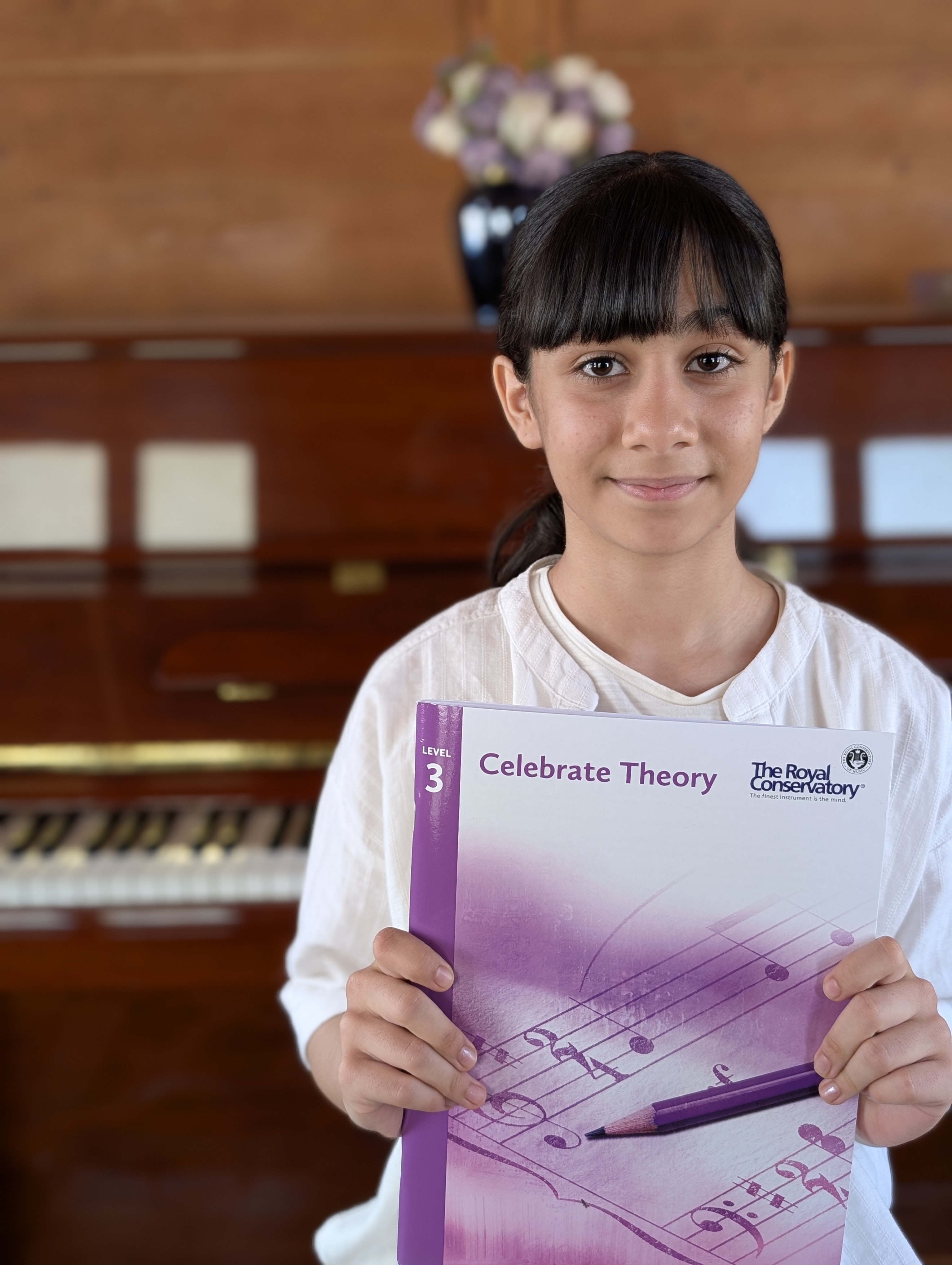 Student holding RCM Celebrate Theory Level 3 book